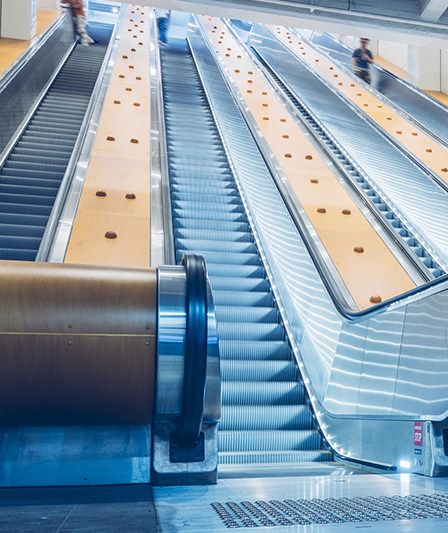 Escalators in a railway station with yellow void in-fills