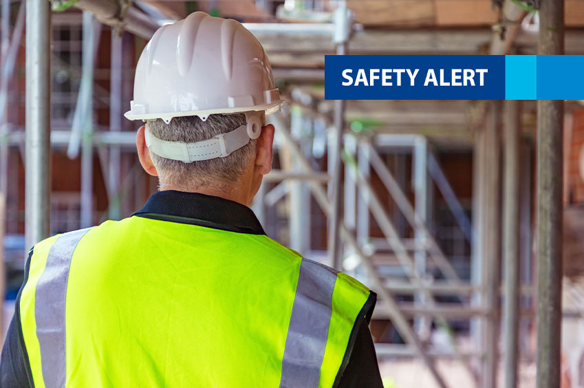 Man wearing hard hat and high vis vest looking out to scaffolding